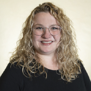 headshot of leigh kolb, a person with curly blond hair and glasses